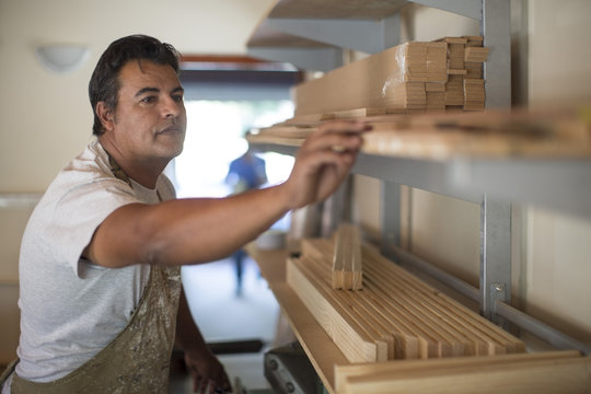 Man with wooden frames on shelf in canvas workshop