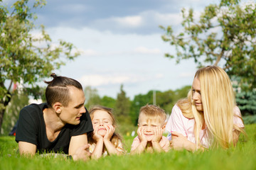 Naklejka na ściany i meble Portrait of happy parents with kids lying at the park