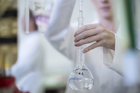 Scientist in lab holding round-bottom flask