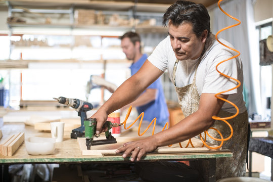 Man drilling frames in canvas workshop
