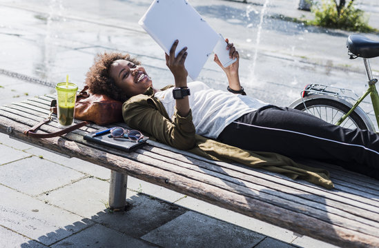 Smiling woman lying on a bench reading notes