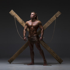 Sexual naked man, muscular, hands tied rope to wooden beams