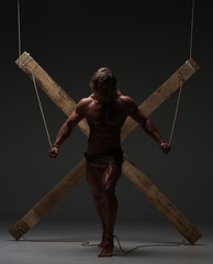Sexual naked man, muscular, hands tied rope to wooden beams