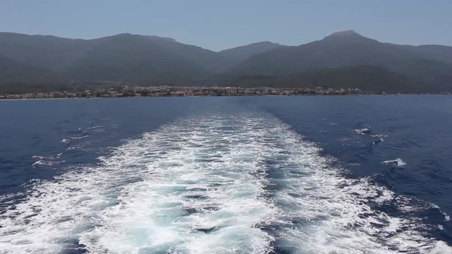 Wake of cruise ship with view of distant coastline