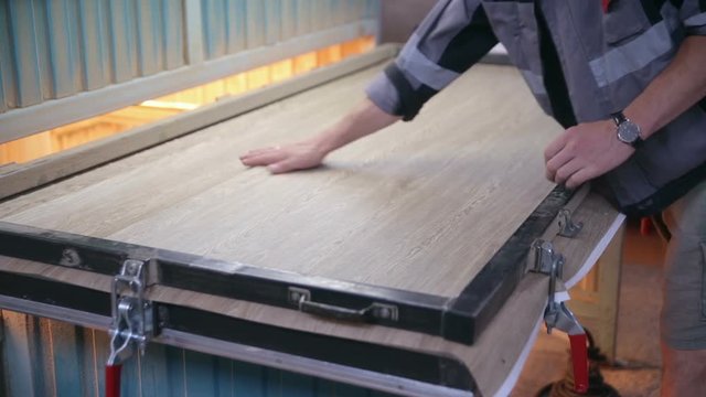 Man puts wooden door into automated Hydraulic press. 1080p.