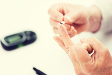 senior woman with glucometer checking blood sugar