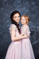 Fototapeta na wymiar Portrait of mother and daughter in identical dresses. Familylook