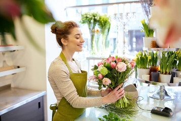 smiling florist woman making bunch at flower shop - Powered by Adobe