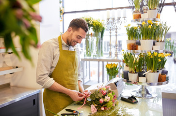 smiling florist man making bunch at flower shop - obrazy, fototapety, plakaty