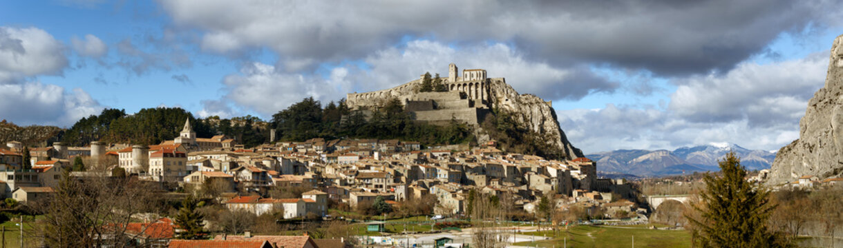 Panoramic view of Sisteron rooftops and the Citadel in summer light with clouds. The Sisteron Citadel and its fortifications is located in the Southern Alps (Alpes de Haute Provence), France