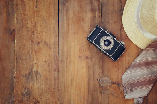 Vintage camera, glasses and fedora hat on wooden table