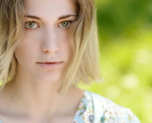 Fototapeta premium Outdoors portrait of beautiful young woman with green eyes.