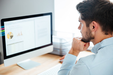 Obraz premium Side view of young confident businessman with laptop in office
