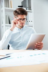 Close-up portrait of a pensive businessman using tablet computer