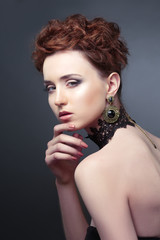 Beauty portrait of elegant girl with large earrings holding a hand on face