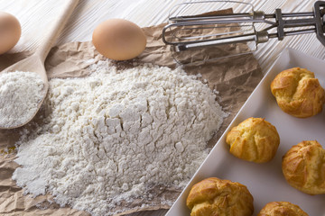 Tasty eclairs, eggs, flour and handle mixer.