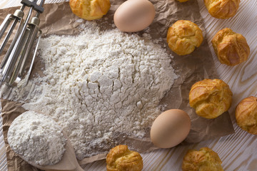Tasty eclairs, eggs, flour and handle mixer.
