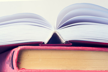 Open book, stack of colorful hardback books on light table. Back to school. Copy space for text