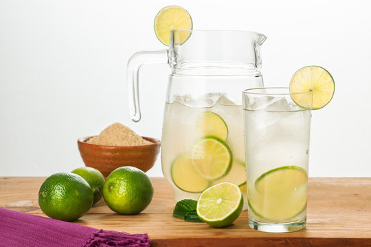 Pitcher and glass of cold lemonade with fresh lemons.