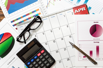 Obraz premium Calculator, glasses, calendar and pen on the graphs