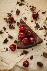 Piece of chocolate cake with cherries on craft paper