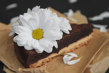 Piece of chocolate cake with flowers on craft paper