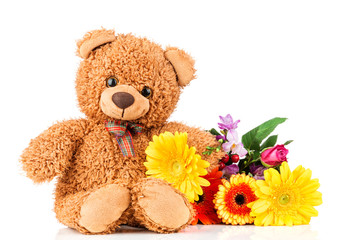 Bunch of mixed beautiful flowers and a teddy bear on white background