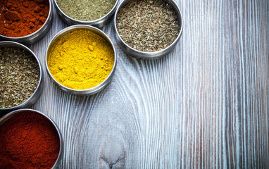 Spices and herbs in metal containers on wooden table