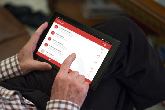 Old man uding his tablet with a fictional email inbox screen
