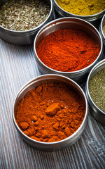 Spices and herbs in metal containers on wooden table