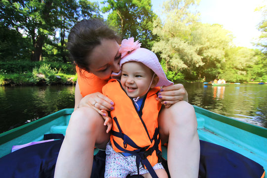Mother and her daughter in orange life jacket sitting on the boat