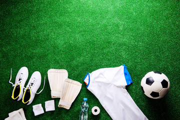 Soccer ball,cleats and various football stuff against artificial