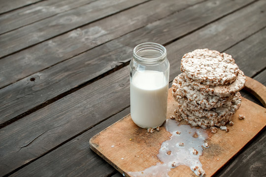 Glass jar of homemade milk, delicious crispbread on wooden background table