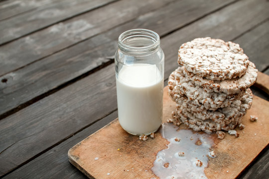 Glass jar of homemade milk, delicious crispbread on wooden background table
