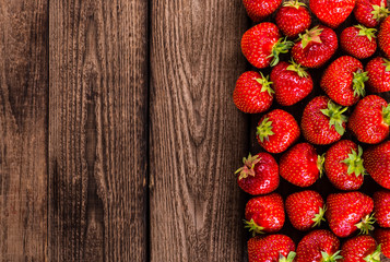 Strawberry on wood background. Strawberry with green leaves.