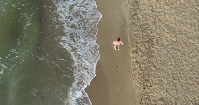 Morning jogging guy along the surf line of the sea beach in summer