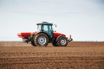 Obraz premium Farmer fertilizing arable land with nitrogen, phosphorus, potassium fertilizer