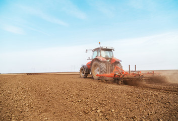 Tractor cultivating field at spring