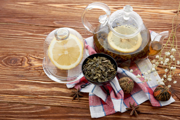 Fototapeta na wymiar Ripe lemon, cinnamon and fruit drink in glass teapot on wooden background