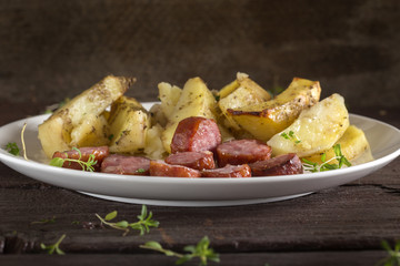 Plate with fried potato with sausages and spices