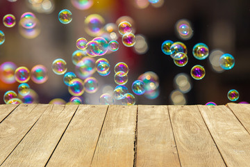Empty wooden table or plank with bokeh of rainbow soap bubbles from the bubble blower on background...