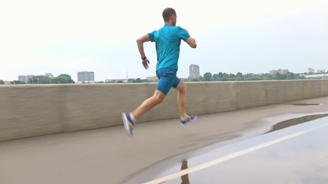 Man in blue uniform running along embankment. Steadicam 4K video
