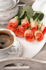 cup of coffee and a bouquet of roses on a tray