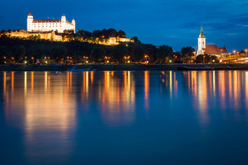 Bratislava castle and St. Martin's cathedral with it's reflection in Danube river after sunset, Slovakia