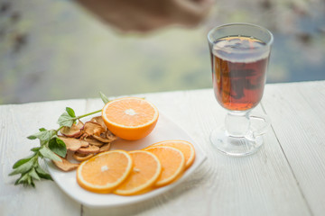 Shot of glass cup of tea with orange on wood table