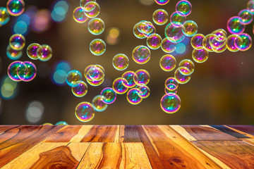 Empty painted wooden table or plank with bokeh of rainbow soap bubbles from the bubble blower on background for product display.