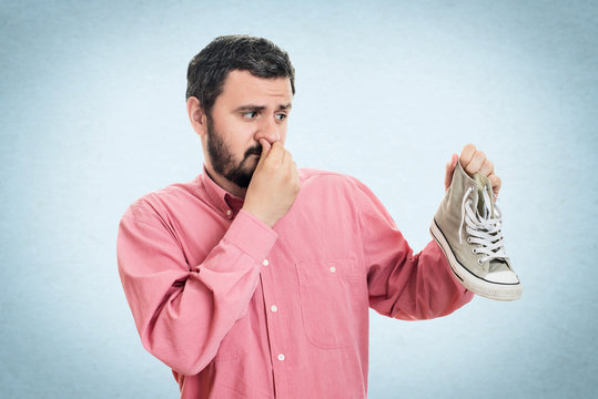 Man holding dirty stinky shoe. Unpleasant smell stink