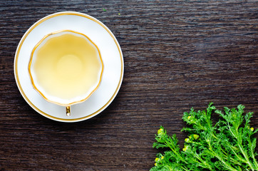 herbal matricaria chamomile tea in a porcelain cup on a dark wooden background