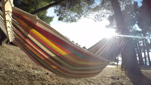 4K : Swinging in hammock in summer vacation resort with sun in the background