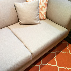 Gray sofa with cushions on orange carpet